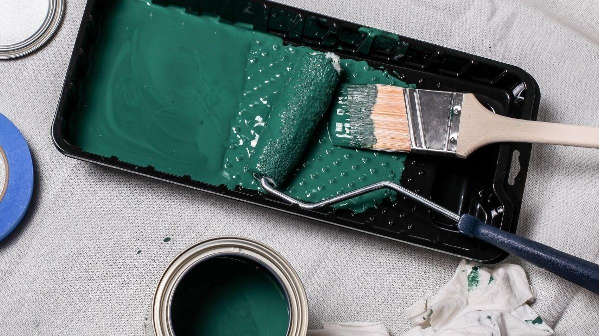 A paint tray and brush with green latex paint
