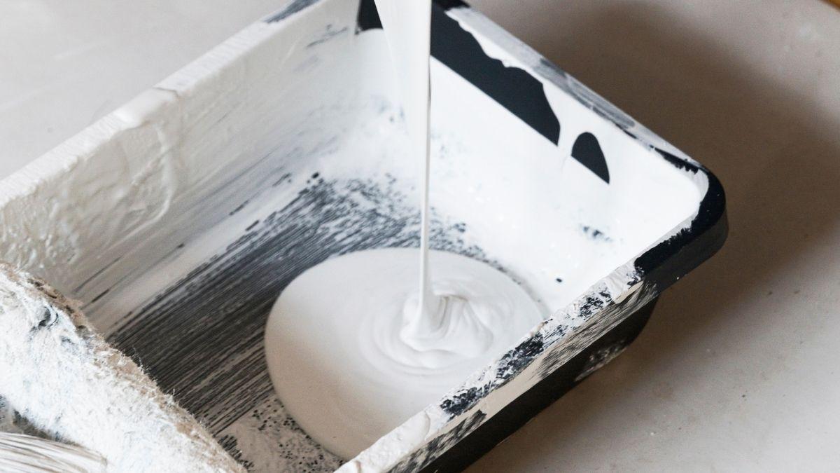 Pouring white paint into a paint tray