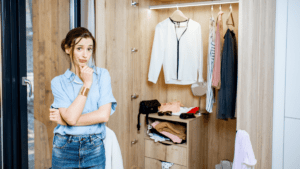 woman looking quizzical standing in front of an open wardrobe of clothes
