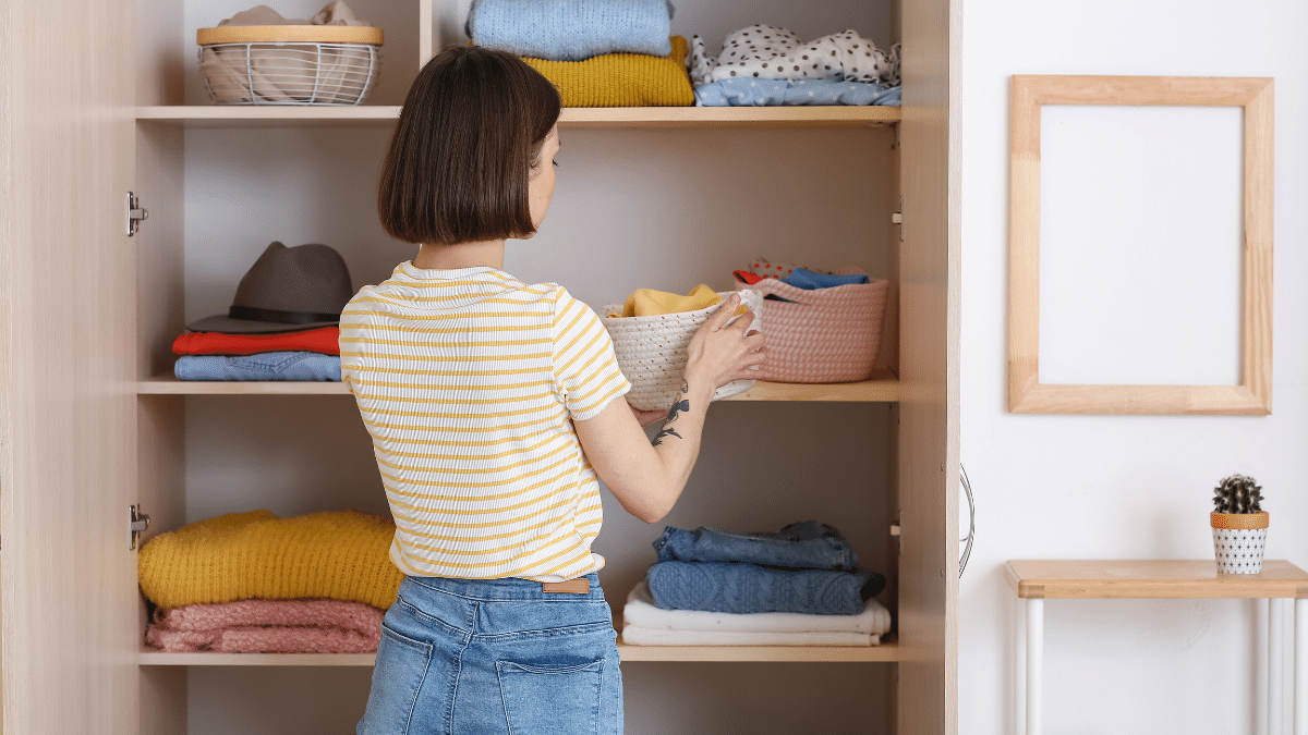 woman in yellow and white striped t-shirt with back to the camera organising a wardrobe