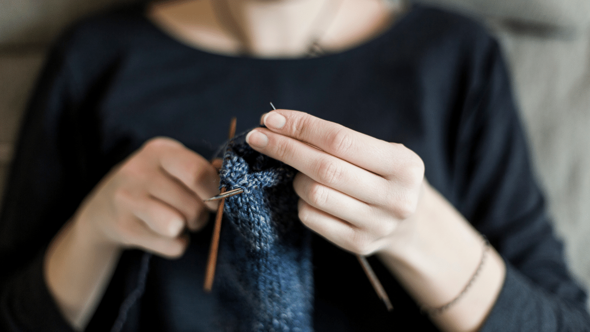 close up of woman knitting with blue fabric